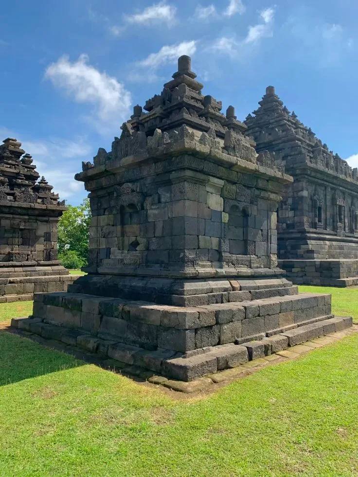 Candi-candi batu di hamparan rumput Candi Ijo di bawah langit biru cerah